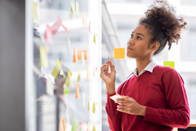 Mujer mirando notas "post-its" sobre superficie de metacrilato