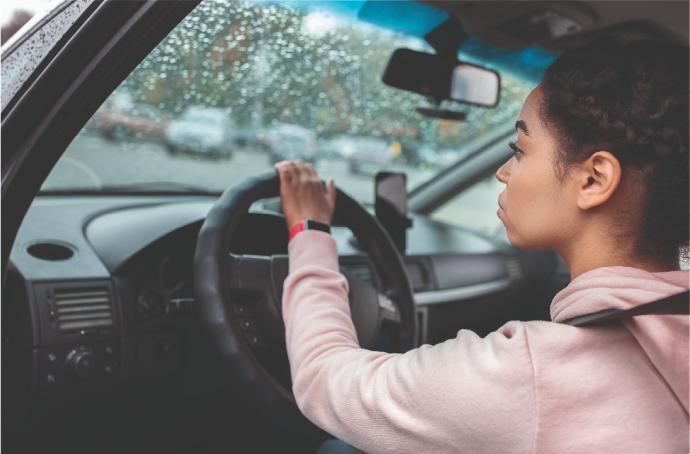 Bajas Mujer conduciendo coche bajo la lluvia